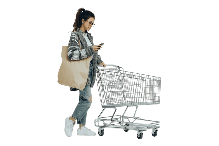 Young woman uses her phone while shopping with reusable tote bag and shopping cart.