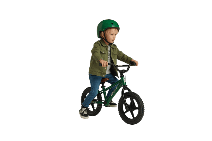 Young child riding green balance bike with helmet