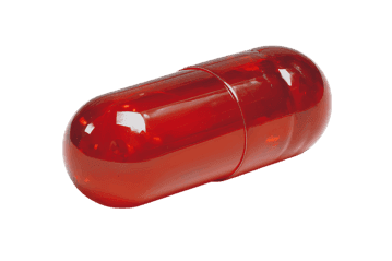 Single red capsule isolated on black background.