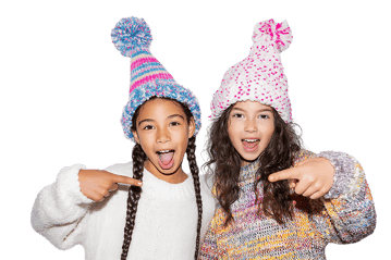 Two girls in winter hats point playfully.