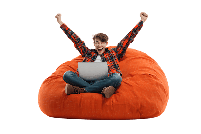 Excited young man using laptop on orange beanbag chair