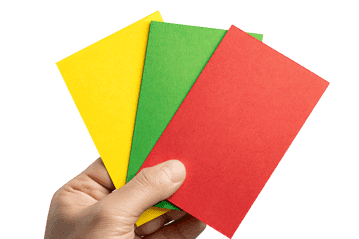 Close up of a hand holding yellow, green and red referee cards.
