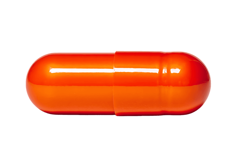 Close up of a single orange capsule pill isolated on black background.