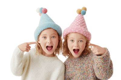 Two girls in party hats point at themselves.