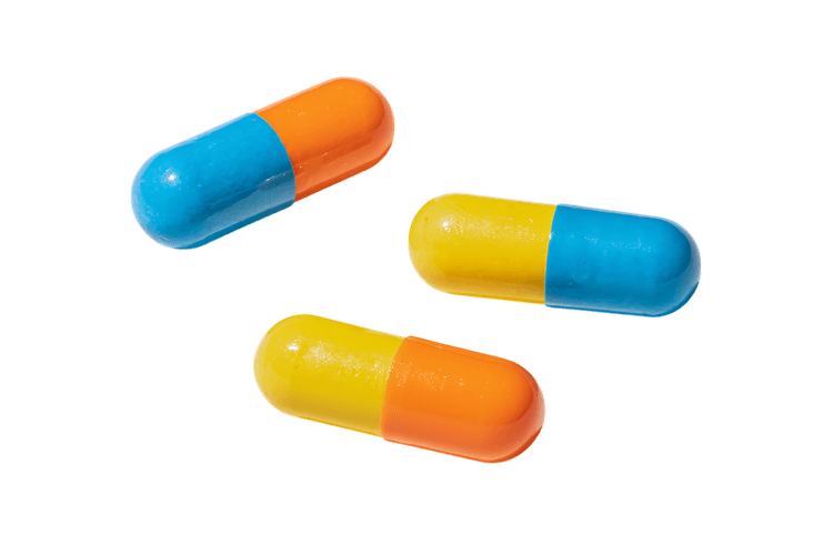 Three vibrant capsules, blue, yellow, and orange. Medical concept.