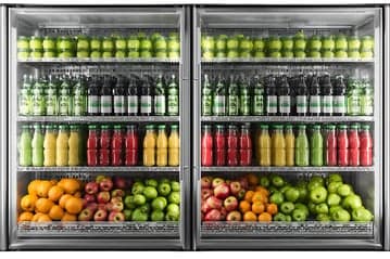 Refrigerated display with fresh juices, fruits, and drinks.